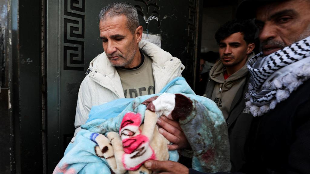 Un hombre sostiene a un bebé en brazos después de los ataques de Israel a Gaza.