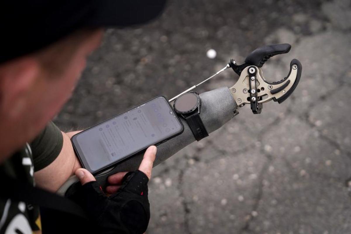Un excombatiente ucraniano mutilado sostiene su móvil en su brazo artificial durante una visita a Madrid