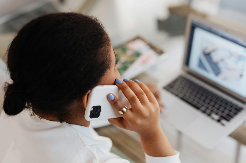 mujer hablando por teléfono frente a la computadora