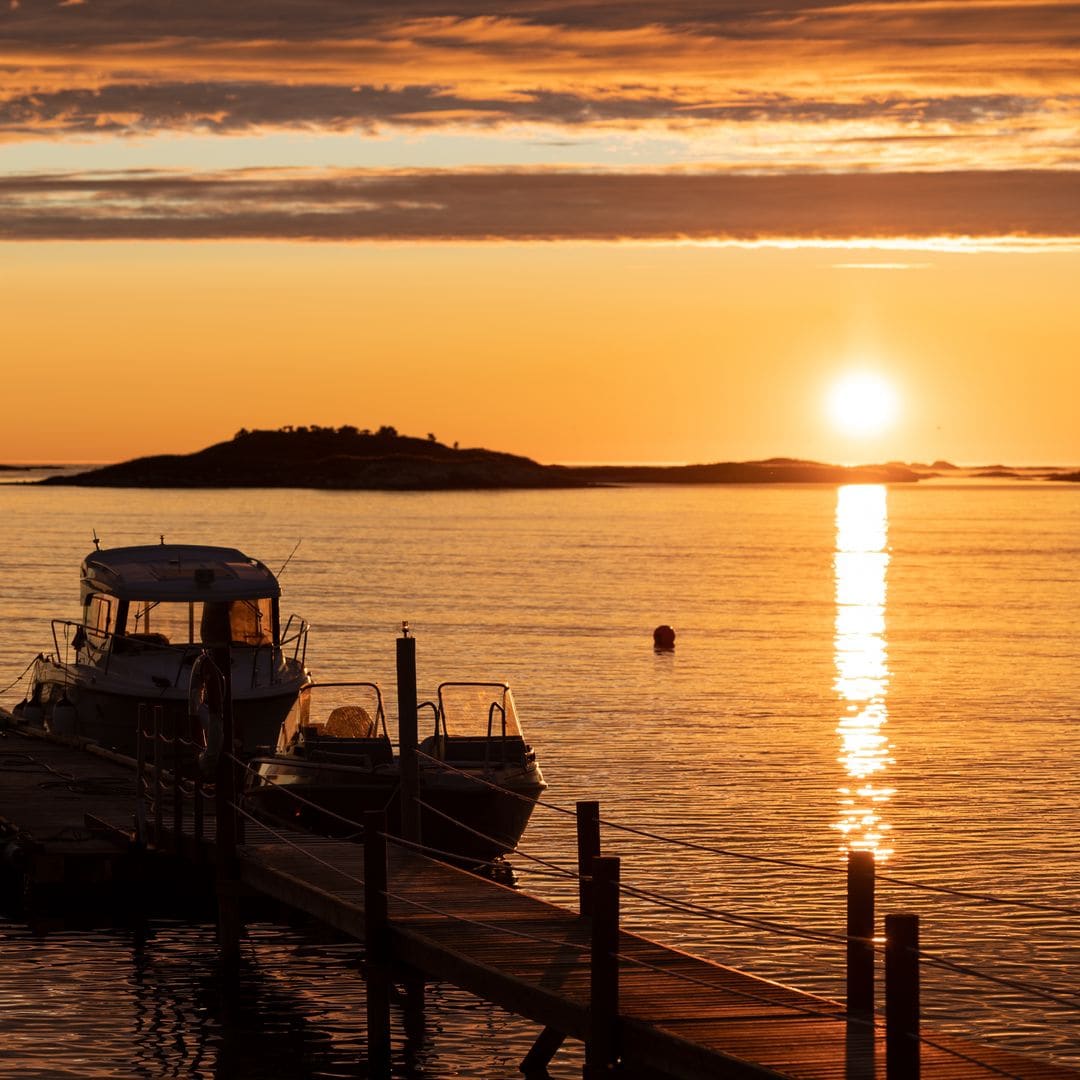 Barcos amarrados en el puerto bajo el sol de medianoche, isla de Sommarøy, Noruega