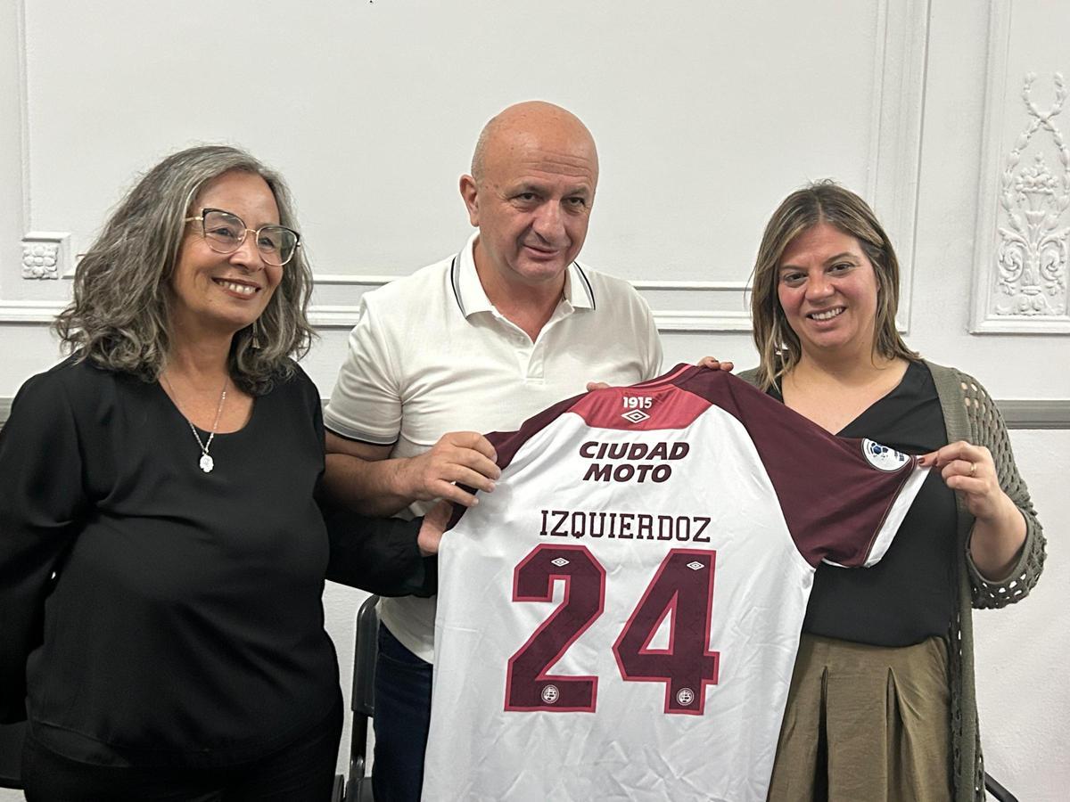 Nicolás Russo entrega a Gimena Llamedo la camiseta de Izquierdoz junto al Secretario de Educación y Cultura del Concejo Deliberante de Lanús.