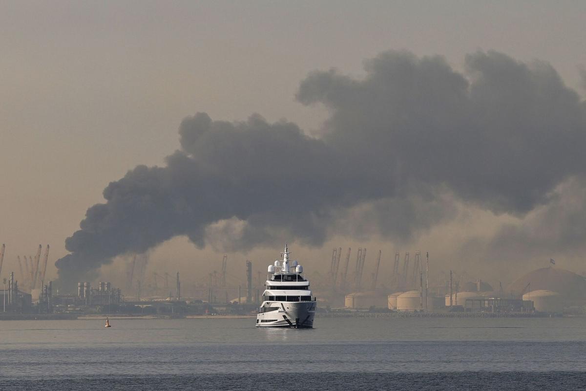 Un yate en el puerto de Jebel Ali, en Dubai, frente a una columna de humo tras un bombardeo de Irán el 1 de marzo.