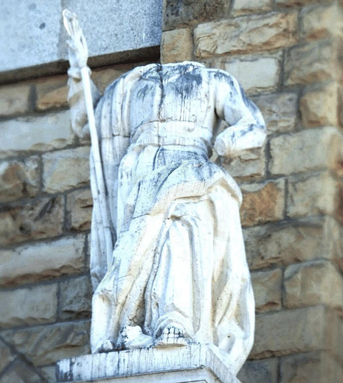 Escultura sin cabeza en la fachada de la iglesia.