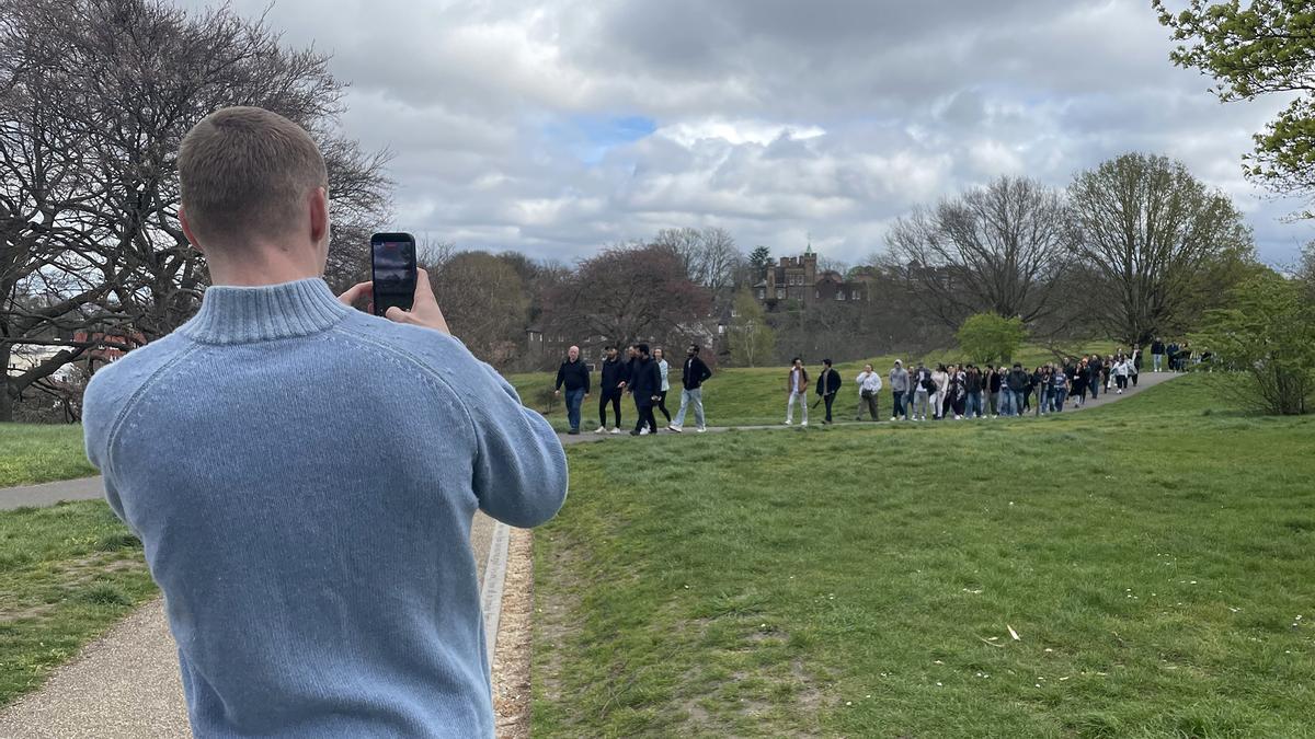 Paseos en grupo para combatir la soledad, en parques y zonas bonitas de Londres. Henry Duff (en primer plano, con un jersey azul) reúne a un centenar de personas, en Greenwich Park, en uno de los paseos que organiza de forma gratuita en Londres a través de TikTok para conocer gente nueva.