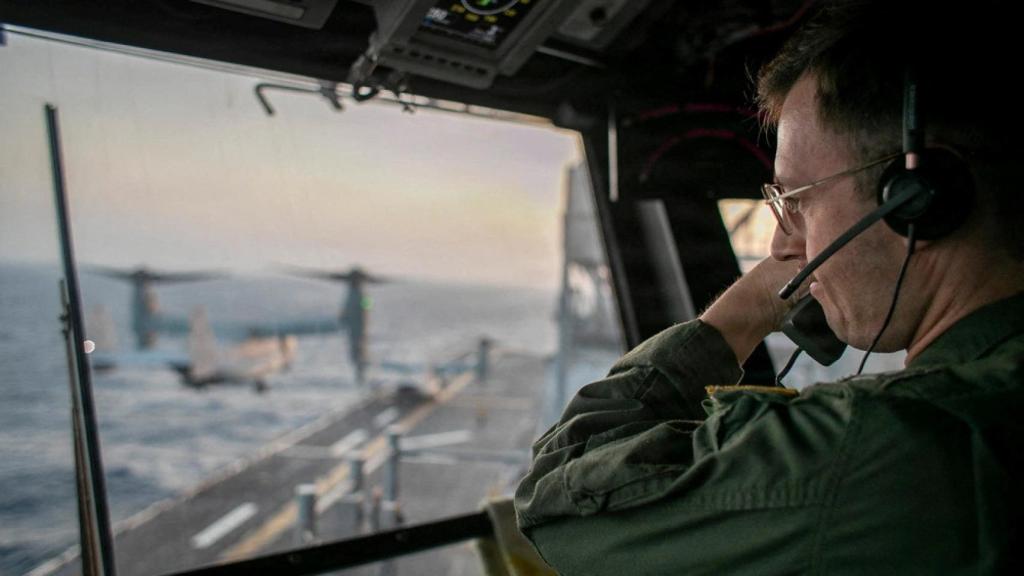 Un oficial supervisa las operaciones en la cubierta de vuelo del USS Tripoli en aguas del Mar Arábigo.