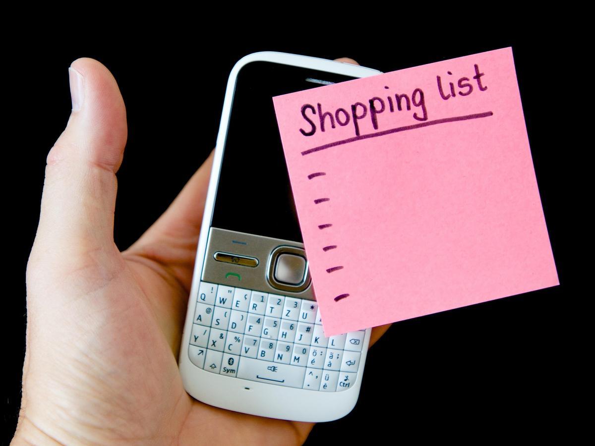 Imagen de una lista de la compra junto a un teléfono móvil.