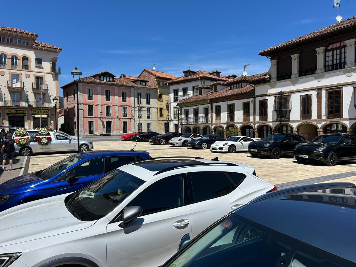 Varios vehículos de la marca Porsche ante la iglesia de Pravia para despedir a los fallecidos.