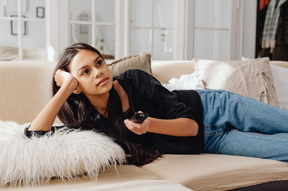 mujer tumbada en el sofá viendo la televisión