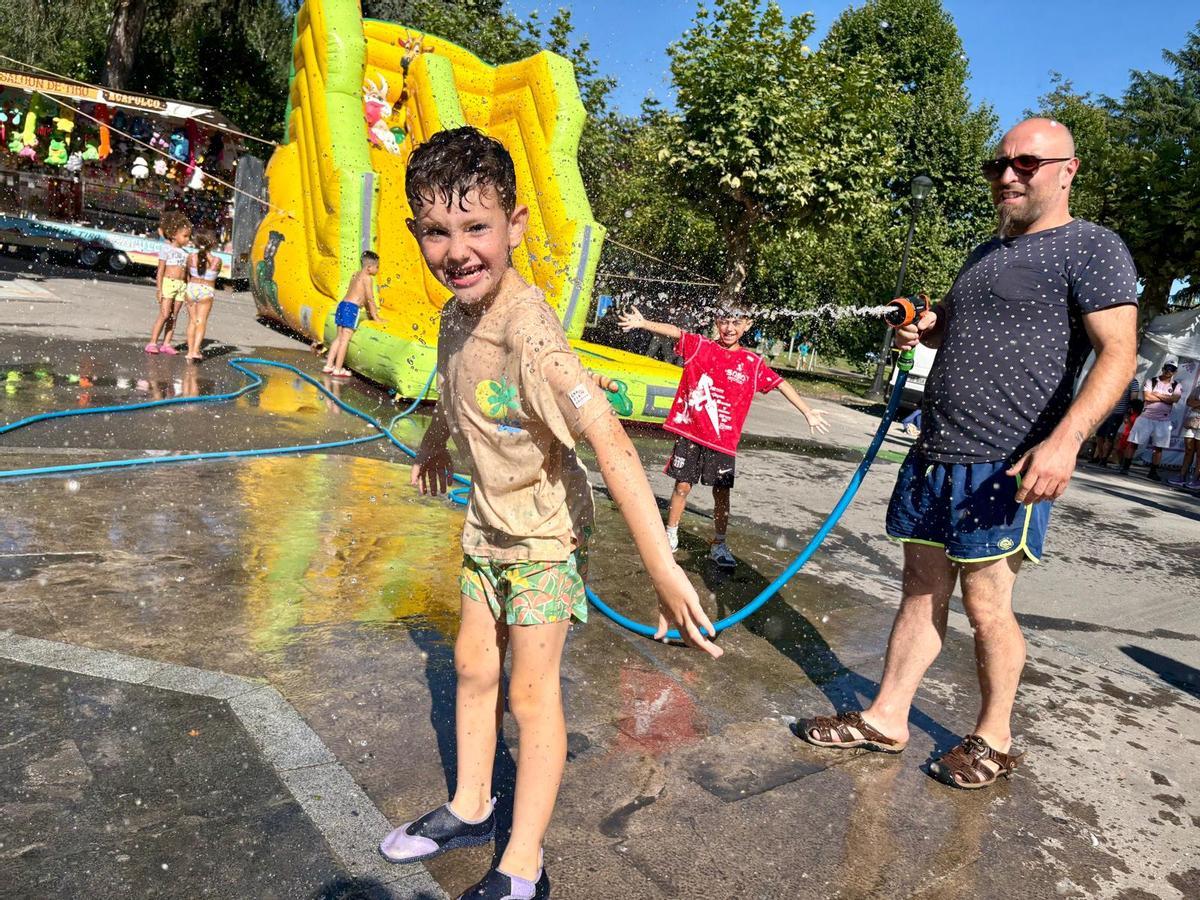 Un niño se divierte con agua en el recorrido de las fiestas de Santiago en Sama