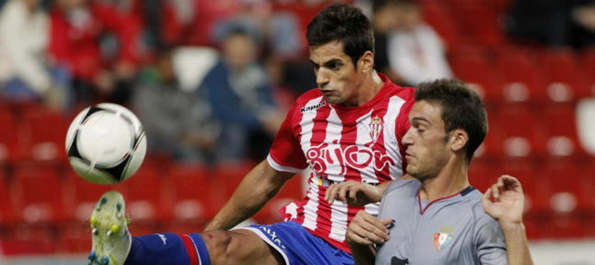 Pedro Orfila (i), defensor del Sporting de Gijón, lucha por el balón con el delantero de Osasuna, Roberto Torres.