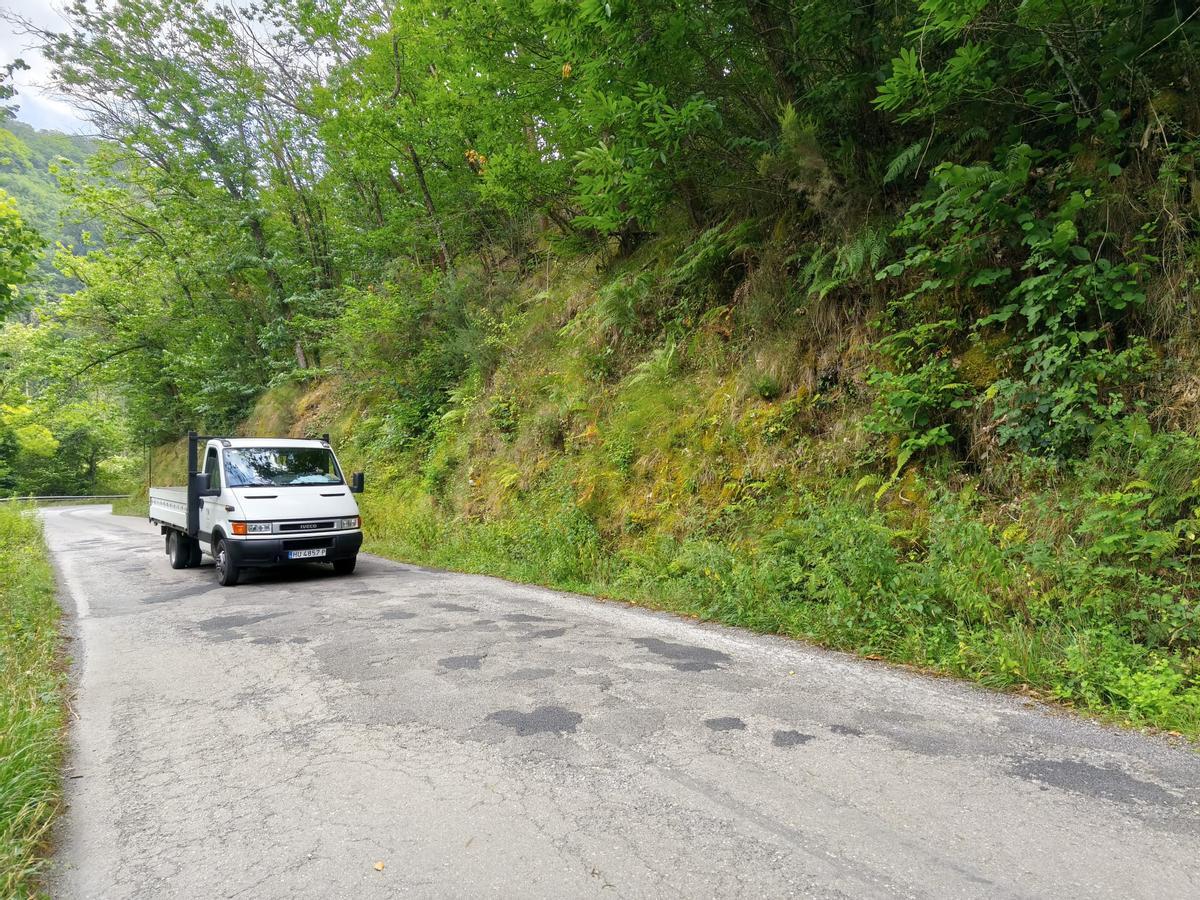 Un camión de trabajo pasa por una zona de baches en la AS-311 entre San Pedro de los Burros y Cubia, en Grado.