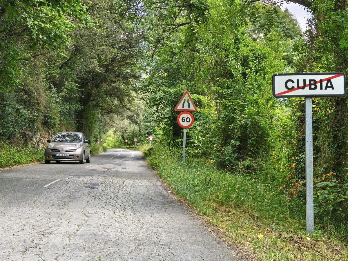 Un vehículo entra en la localidad de Cubia, en Grado, con un gran derrumbe en el carril derecho.