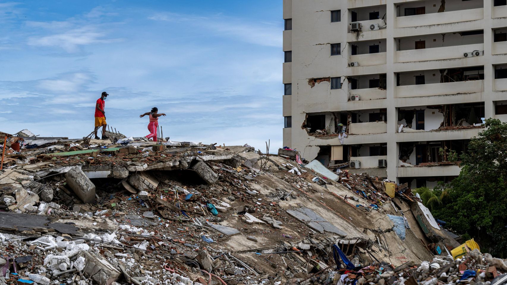 Vecinos caminan sobre los escombros de un edificio derrumbado en Caraballeda, estado de La Guaira.